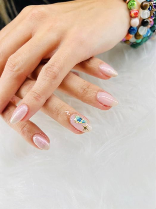 Soft pink nails with gem accent and beaded bracelet